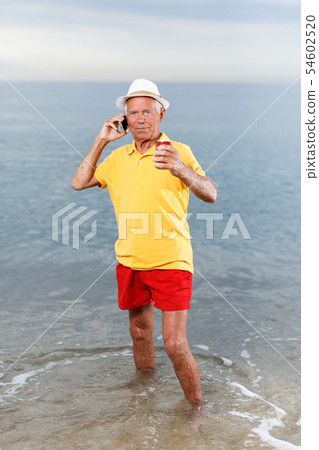 Mature man speaking phone and taking drink Mature man speaking phone and taking drink 54602520