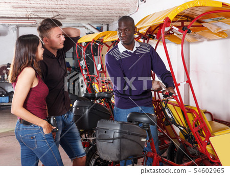 African-American pedicab driver talking to couple, offering rickshaw service African-American pedicab driver talking to couple, offering rickshaw service 54602965