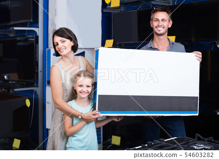 parents with daughter choosing new big TV screen in home appliance store 54603282