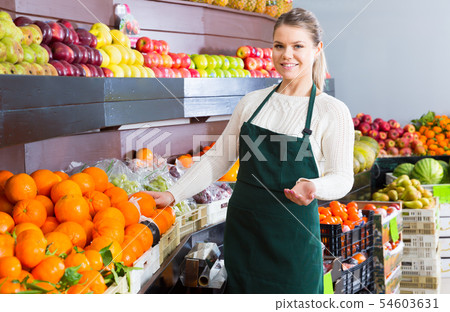 Pretty female in apron selling fresh oranges 54603631