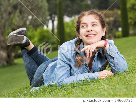 portrait of smiling young girl while lying in outdoors 54603755
