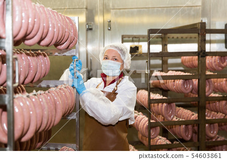 Female carrying sausages on racks Female carrying sausages on racks 54603861