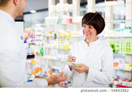 Woman druggist wearing white coat Woman druggist wearing white coat 54603862