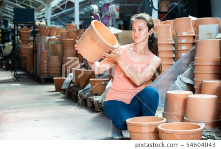 Female seller is standing near clay pots in stock Female seller is standing near clay pots in stock 54604043
