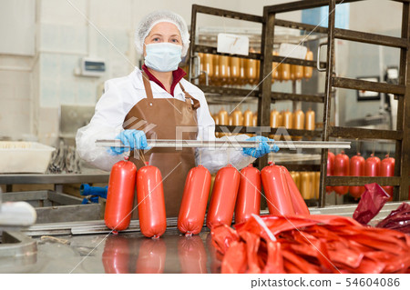 Woman stringing sausages on rail Woman stringing sausages on rail 54604086