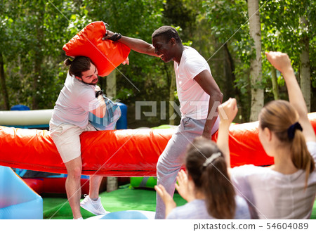 Fun wrestling with pillow in an amusement park on a summer sunny day Fun wrestling with pillow in an amusement park on a summer sunny day 54604089