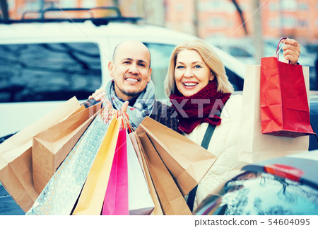 elderly couple carrying purchases and smiling outdoors 54604095