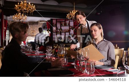 Young female waiter taking order from visitors in luxurious restaurant 54604518