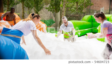 Game of funny friends in soap suds on an inflatable trampoline Game of funny friends in soap suds on an inflatable trampoline 54604723