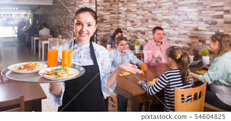 young waitress warmly welcoming guests to family cafe 54604825
