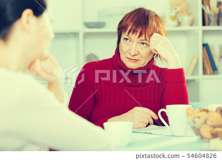 Upset woman with cup of tea talking with daughter 54604826