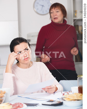 Young woman and mother with financial documents, quarrel Young woman and mother with financial documents, quarrel 54604839
