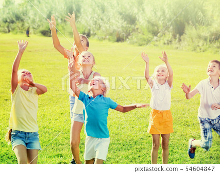 Group of children jumping together on green grass in park Group of children jumping together on green grass in park 54604847