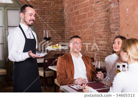 Positive male waiter carrying order for visitors Positive male waiter carrying order for visitors 54605313