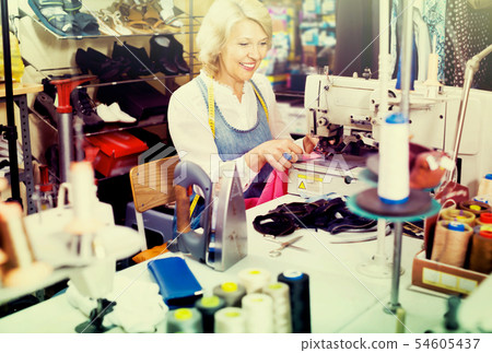 middle-aged woman tailor using sewing machine middle-aged woman tailor using sewing machine 54605437