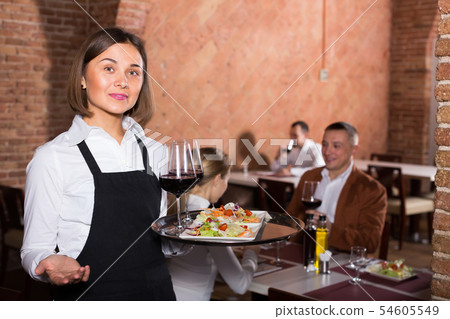 smiling woman waiter demonstrating restaurant to visitors 54605549