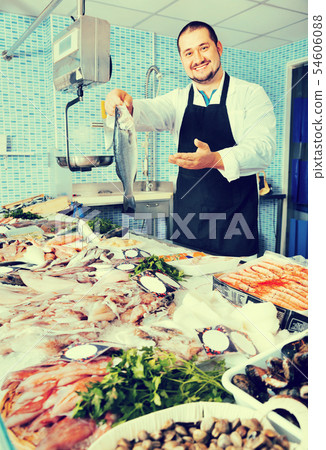Seller behind scales and fish counter showing fish 54606088