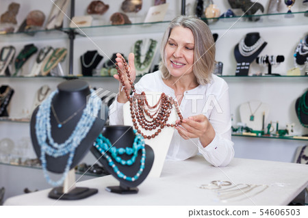 Woman offering to buy fashionable golden stone necklace in the shop of jewelry 54606503