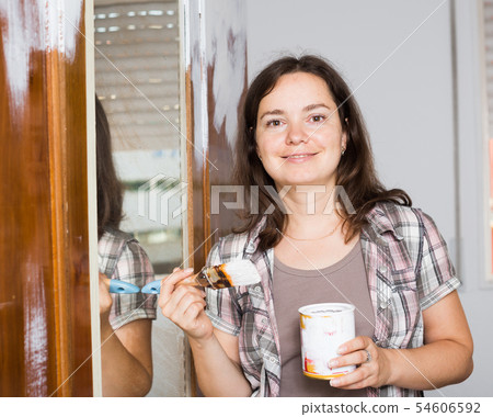 Creative woman is decorating old wardrobe with white paint 54606592