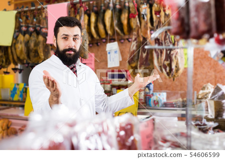 Man shop assistant showing meat in shop 54606599