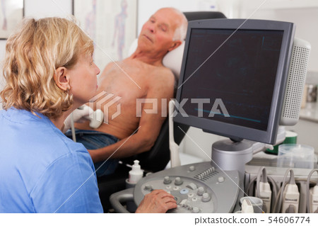 doctor examines a senior man with ultrasonic device doctor examines a senior man with ultrasonic device 54606774