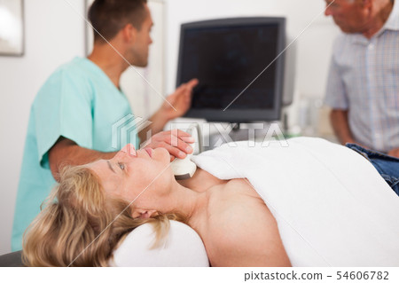 Doctor conducting ultrasound examination of patient's thyroid lying Doctor conducting ultrasound examination of patient's thyroid lying 54606782