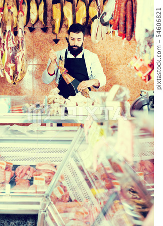 Male shop assistant demonstrating jamon Male shop assistant demonstrating jamon 54606821
