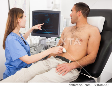 Woman sonographer examining male patient Woman sonographer examining male patient 54606848