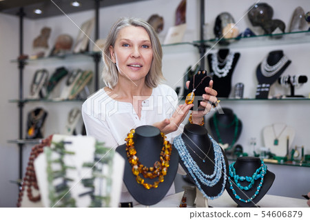 Woman trying on a aventurine necklace and earrings at a jewelry store 54606879