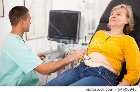 Man sonographer examining female patient Man sonographer examining female patient 54606946