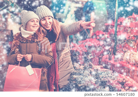 Girl with woman choosing Christmas gifts for family Girl with woman choosing Christmas gifts for family 54607180