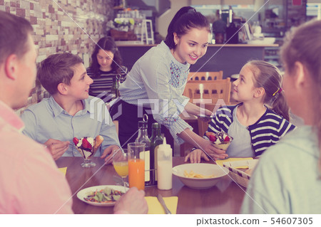 Polite nice waitress serving dishes to family 54607305