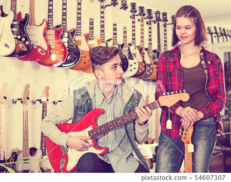 Smiling girl and boy are deciding on suitable amp 54607307