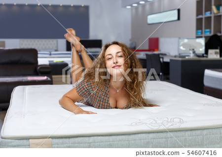 Woman choosing mattress in furnishings store Woman choosing mattress in furnishings store 54607416