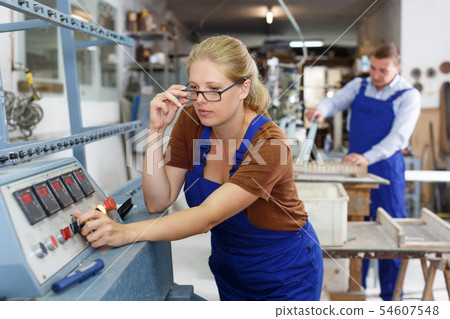 Female glazier working on glass bevelling machine 54607548