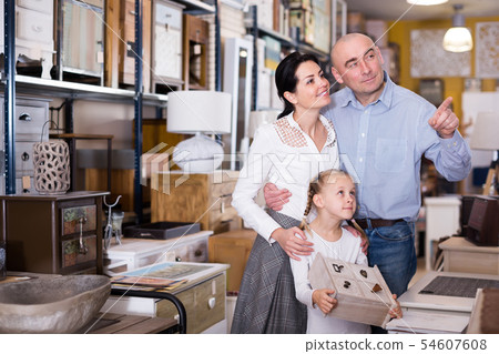 Positive family with young girl choosing furniture for house Positive family with young girl choosing furniture for house 54607608