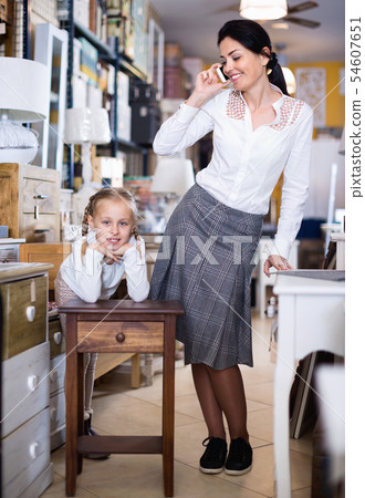 Adult female and her daughter are looking on new furniture in the store. Adult female and her daughter are looking on new furniture in the store. 54607651