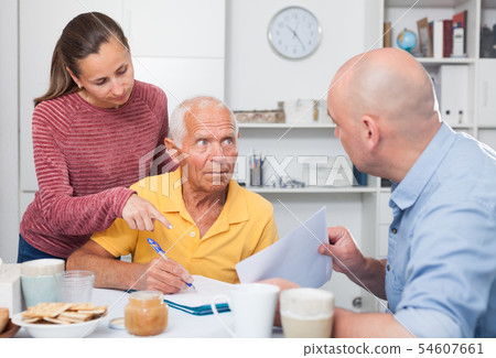 Mature father and adult children fill out paperwork Mature father and adult children fill out paperwork 54607661