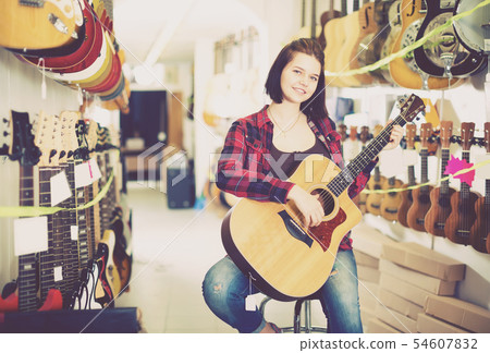 Nice girl examining various acoustic guitars Nice girl examining various acoustic guitars 54607832