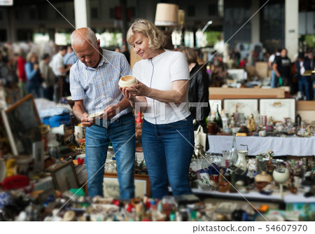 Glad man and woman choosing interesting souvenirs at traditional flea market Glad man and woman choosing interesting souvenirs at traditional flea market 54607970