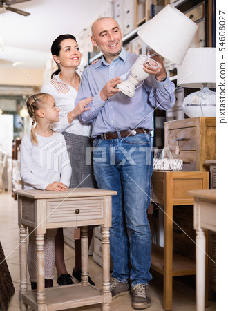 Happy family is choosing new lamp for home in the furniture store. Happy family is choosing new lamp for home in the furniture store. 54608027