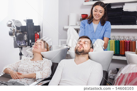 Female professional washing cheerful male's hair in salon Female professional washing cheerful male's hair in salon 54608103