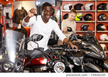 Smiling Afro American man posing near motorcycle Smiling Afro American man posing near motorcycle 54608280