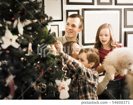 Happy family members decorates Christmas tree Happy family members decorates Christmas tree 54608371