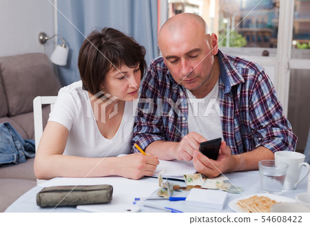 Husband and wife calculate income and expenses on smartphone Husband and wife calculate income and expenses on smartphone 54608422