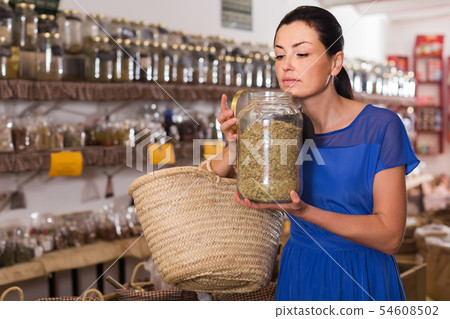 adult female take a smell natural dried herbs sold by weight in eco shop 54608502