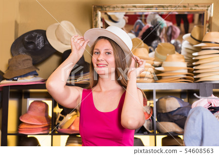 young blonde woman choose straw hat in shop 54608563