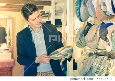 portrait of young male try on flat hat at the shopping mall 54608608