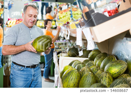 Adult man is choosing ripe melon in the store 54608687
