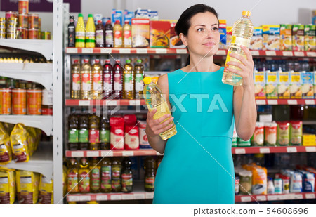 Woman choosing different oil in bottle Woman choosing different oil in bottle 54608696